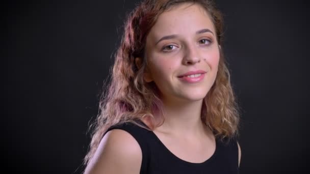 Retrato de jovem caucasiana com cabelo rosa piscando para a câmera e sorrindo no fundo preto . — Vídeo de Stock