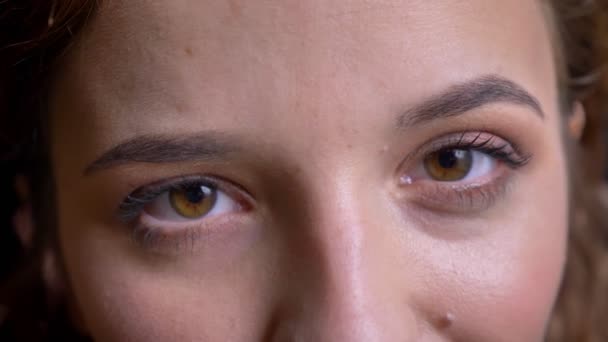 Primer plano retrato de una joven caucásica abriendo los ojos y mirando a la cámara sobre fondo negro . — Vídeos de Stock