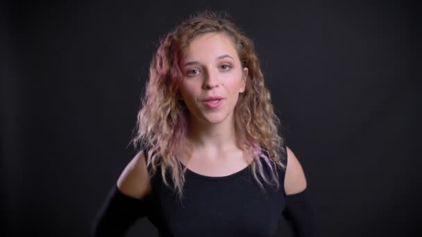 Porträtt av unga kaukasiska flicka med rosa hår hoppar glatt på svart bakgrund. — Stockvideo