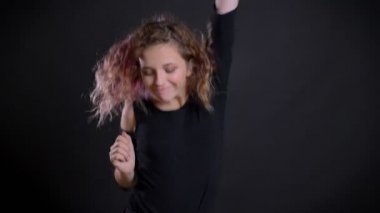 Pembe saçlı sevinçle ve garip bir şekilde siyah arka plan üzerine dans babacan Genç beyaz kız portresi.