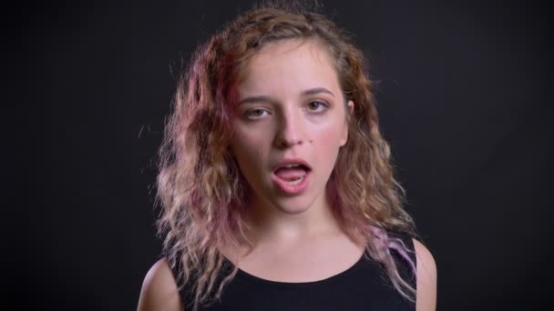 Portrait de easygoing jeune fille caucasienne avec des cheveux roses joyeusement faire des visages étranges sur fond noir . — Video