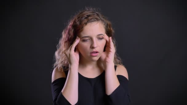 Retrato de chica caucásica joven con pelo rosa haciendo masaje de dolor de cabeza sobre fondo negro . — Vídeos de Stock