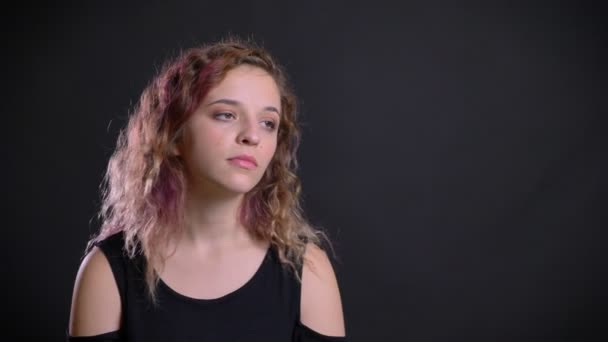 Портрет скучающей молодой кавказской девушки с розовыми волосами, не имеющей ничего общего с черным фоном . — стоковое видео