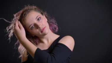 Genç beyaz pembe saçlı kız flirtingly içine kamera siyah arka plan üzerine saçını sallayarak portresi.