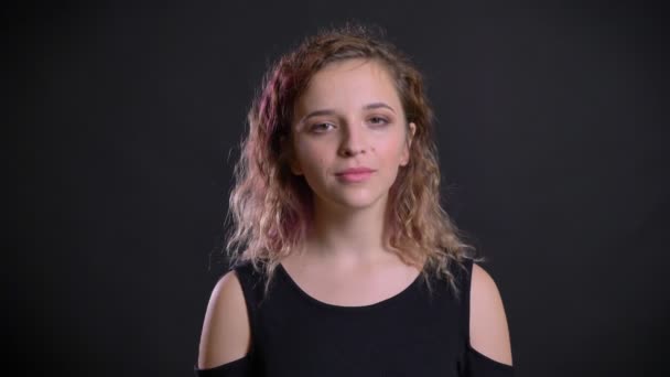 Portrait of young caucasian girl with pink hair approvingly nodding into camera on black background. — Stock Video