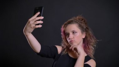 Selfie-fotoğrafları yapma pembe saçlı Genç beyaz kız portresi siyah arka plan üzerine smartphone kullanarak.