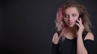 Sevinçle cep telefonu siyah arka plan üzerine konuşurken pembe saçlı Genç beyaz kız portresi.