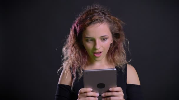 Portrét, kavkazský dívky, s růžovými vlasy dívat do tabletu dostane šokován a ukazuje displej do kamery s jako znamení. — Stock video