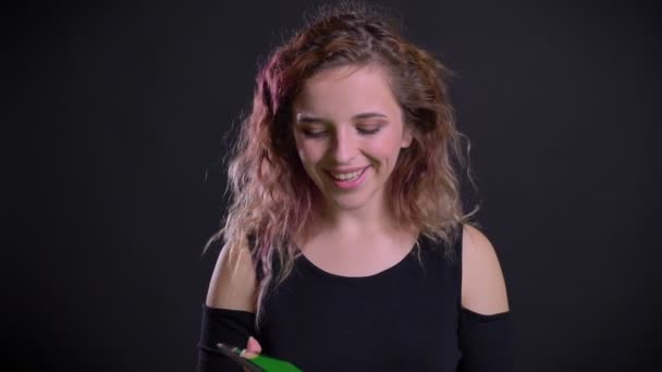 Retrato de alegre chica caucásica con el pelo rosa mirando en la tableta se sorprende y muestra la pantalla en la cámara con signo similar . — Vídeo de stock