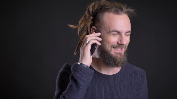 Freaky hombre caucásico de mediana edad con rastas y piercing hablando en el teléfono celular sobre fondo negro . — Vídeo de stock