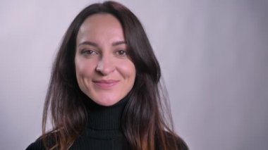 Yüzlerinde izliyor ve kamera gri arka plan üzerinde yanıp sönen genç Kafkas esmer kadın portresi.