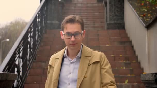 Gros plan de l'homme caucasien attrayant descendant les escaliers et regardant directement la caméra dans le parc à l'extérieur dans une journée d'automne — Video