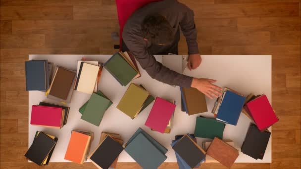 Stop motion top shot of man moving his hand above the disappearing books on table downloading them on tablet. — Stock Video