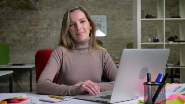 Closeup portret van met behulp van laptop glimlachen en kijken recht op de camera vriendelijk mooie vrouwelijke beambte — Stockvideo