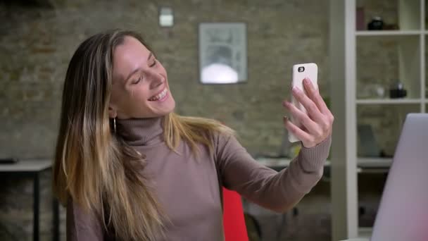 Closeup portrait of attractive female employee having a video call waving hello and smiling on the workplace — Stock Video