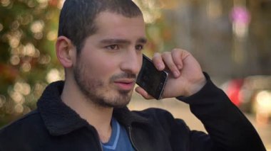 Dikkatle sokak arka plan telefonda konuşurken Genç beyaz adam portresi