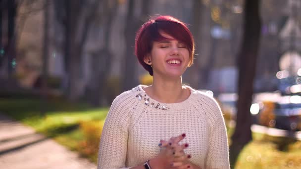 Portrait of young caucasian pink-haired girl with arms crossed smiling humbly and happily into camera in autumnal park. — Stock Video