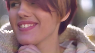 Gülümseyen ve sonbahar park arka plan üzerinde kamera ile flört güzel genç beyaz pembe saçlı kız portresi yakın çekim.