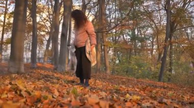 Sonbahar Park'ta yürüyordunuz ve yaprak toplama Genç beyaz kıvırcık saçlı kadın portresi çember.