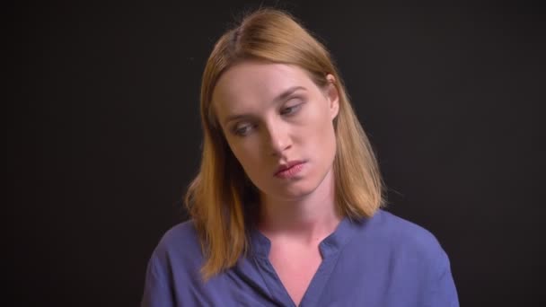 Портрет втомленої жінки, яка дивиться в камеру з пасивністю на чорному тлі . — стокове відео