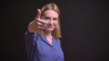 Gibi göstermek ve siyah arka plan üzerine saygı için parmak-up işareti işaret çekici beyaz sarışın kadın portresi.