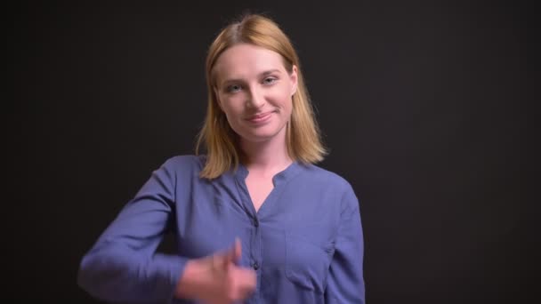 Portrait of young caucasian blonde woman gesturing finger-up sign to show like and respect on black background. — Stock Video
