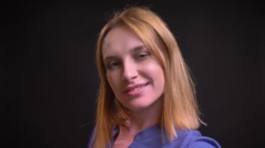 Öz-video selfie-fotoğrafları yapma tişörtlü beyaz sarışın kadının siyah arka plan üzerine smartphone kullanarak.