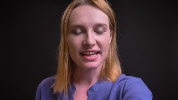 Self-video de mujer rubia caucásica en camisa hablando en videochat usando teléfono inteligente sobre fondo negro . — Vídeos de Stock