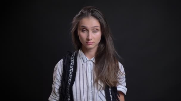 Retrato de una joven caucásica de pelo largo mirando en serio a la cámara sobre fondo negro . — Vídeos de Stock