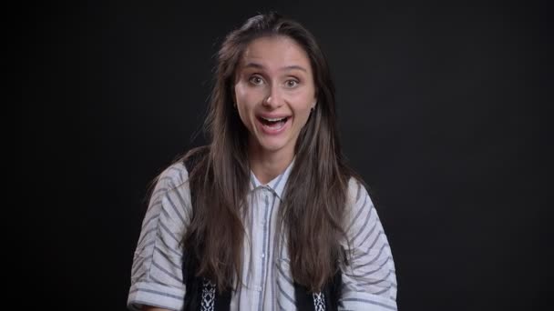 Portrait de surprise jeune femme caucasienne aux cheveux longs riant devant la caméra sur fond noir . — Video