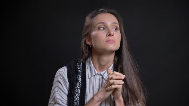 Portrait of young caucasian long-haired woman thoughtfully watching into camera gets insight on black background. — Stock Video