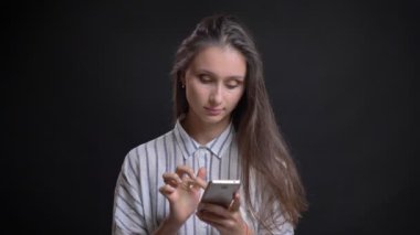 Düşünceli smartphone ile siyah arka plan üzerine çalışan güzel beyaz uzun saçlı kadın portresi.