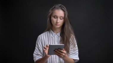 Düşünceli tablet ile siyah arka plan üzerine çalışan güzel beyaz uzun saçlı kadın portresi.