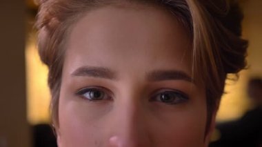 Yakın çekim göz-portresi genç çekici kısa saçlı kadın sakin bir şekilde içine office kamerada izlerken