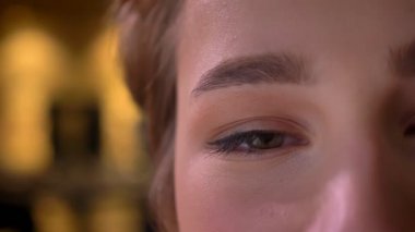 Yakın çekim yarı-portresi genç çekici kısa saçlı kadın ofiste sakin gülümseme ile kamera içine izlerken.