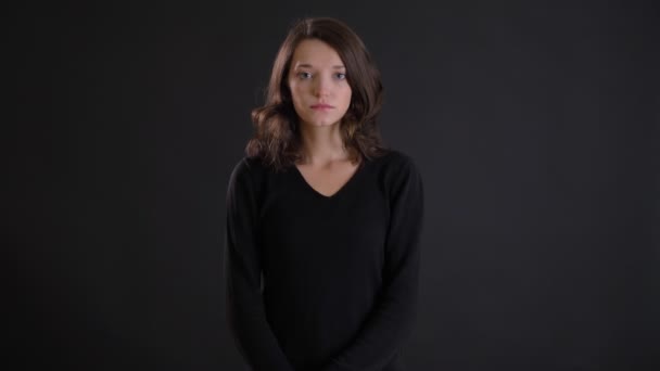 Retrato de joven atractiva caucásica de pelo largo chica mirando con calma en la cámara sobre fondo negro . — Vídeos de Stock