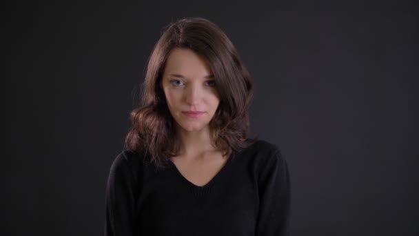 Porträt eines jungen attraktiven kaukasischen langhaarigen Mädchens, das bescheiden in die Kamera auf schwarzem Hintergrund lächelt. — Stockvideo