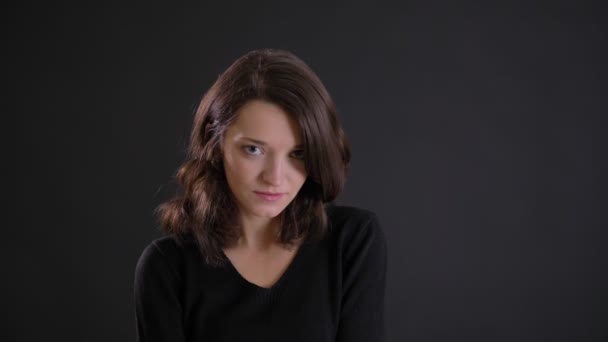 Porträt der jungen attraktiven kaukasischen langhaarigen Mädchen schüchtern in die Kamera auf schwarzem Hintergrund. — Stockvideo