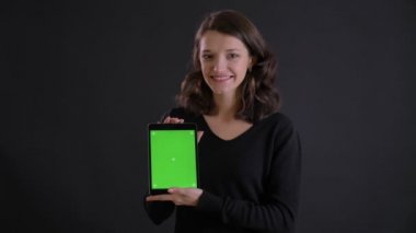 Genç beyaz uzun saçlı kız gülümseyerek kameraya tablet yeşil ekran siyah arka plan üzerinde gösterilen portresi.