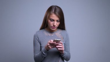 Portre rahat dönüm ve kamera gülümseyen seyir telefon tarama Genç beyaz kadın portresi