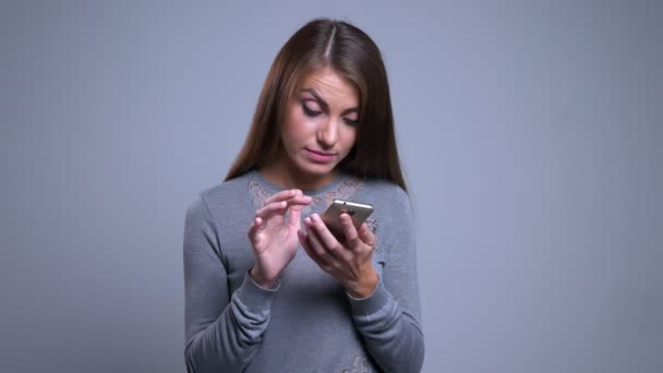 Retrato de close-up de moderno jovem caucasiano feminino usando telefone e ficar irritado ao verificar posts de mídia social — Vídeo de Stock