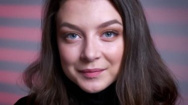 Doğruca kameraya bakarak ve nazikçe gülümseyen güzel genç beyaz kadın yüzü closeup