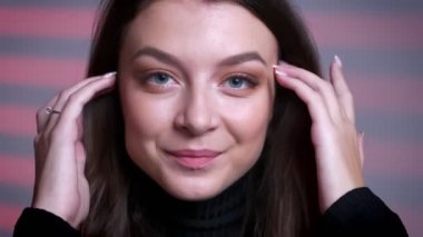 Kameraya bakarak ve saçlarını sabitleme büyüleyici genç beyaz kadın portresi portre