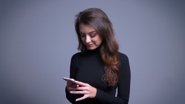 Closeup portrait of modern pretty young female using phone smiling then looking at camera and giggling — Stock Video