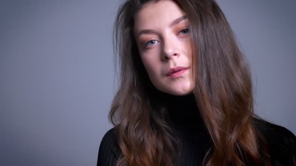 Крупним планом портрет приголомшливої молодої жіночої моделі смоктання волосся за вухом і позує перед камерою — стокове відео