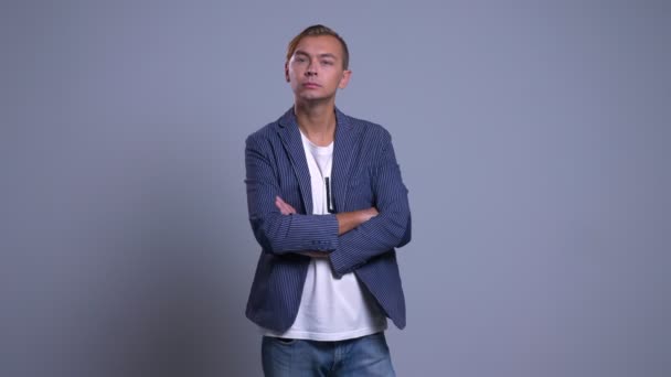 Closeup portrait of young caucasian man standing with a concerned facial expression with his arms crossed over chest — Stock Video