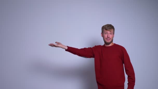 Портрет крупным планом человека, представляющего проект, протягивающий руку вправо, глядя в камеру — стоковое видео