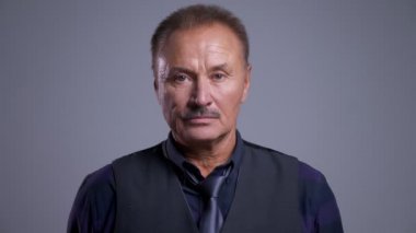 Eldery beyaz adam tarafsız yüz ifadesi ile doğrudan kameraya bakan closeup portresi