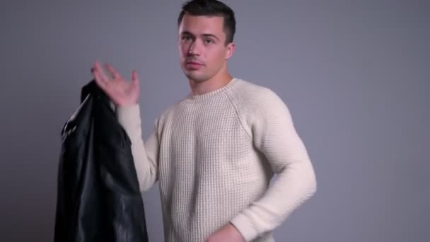 Nahaufnahme Porträt eines attraktiven kaukasischen Mannes, der die Lederjacke über die Schulter wirft, während er in die Kamera blickt — Stockvideo