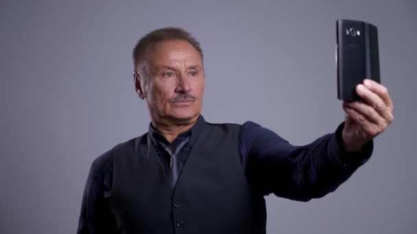 Closeup portrait of eldery caucasian man making selfies and posing making different facial expressions in front of the camera — Stock Video